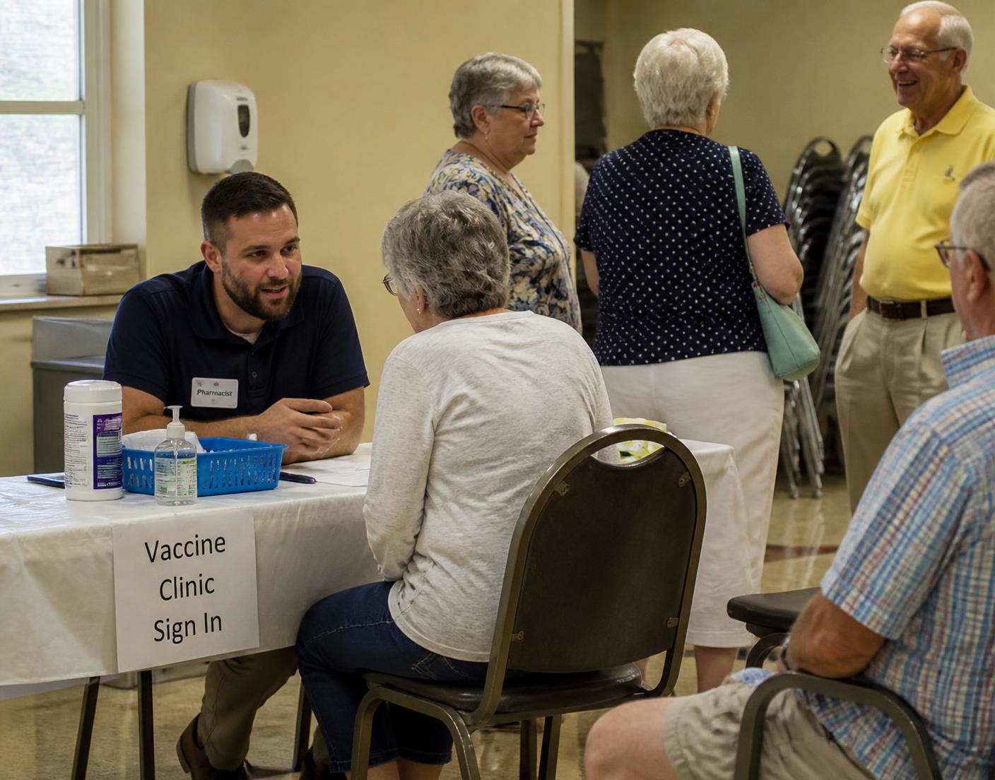 Anchor Pharmacy pharmacist speaking with two senior residents in a sunlit community clubhouse